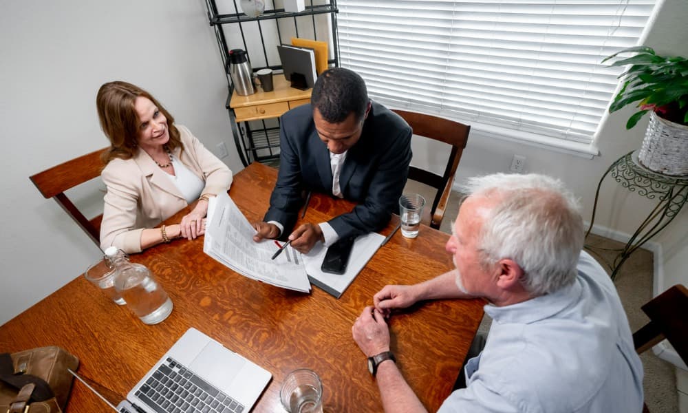 Three people sitting around a table discussing investment opportunities