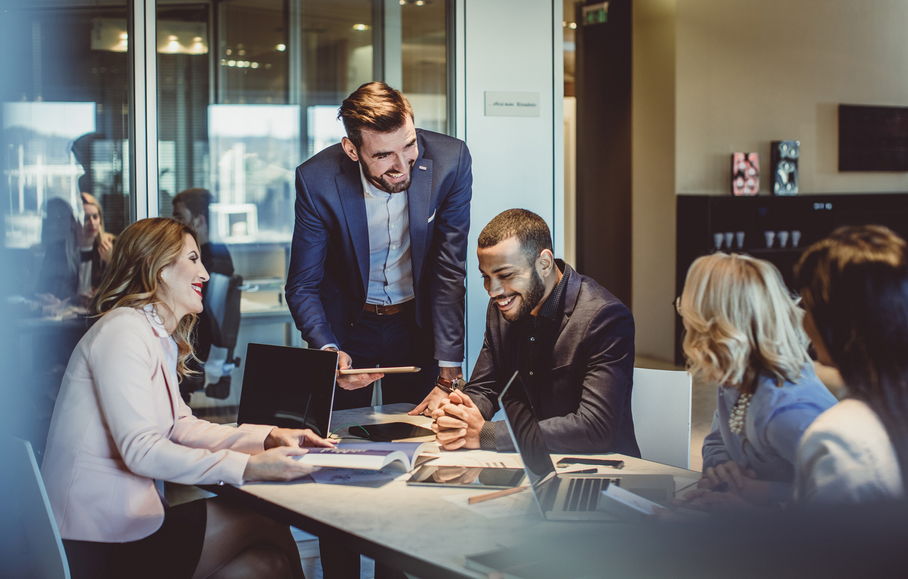 A group of young business people sitting around a conference table and laughing.