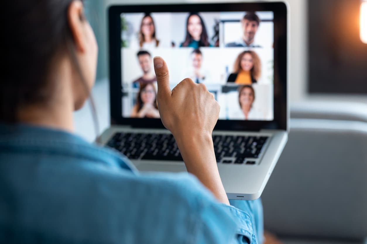 Woman holding a thumbs up and communicating with hybrid sales team through a computer screen