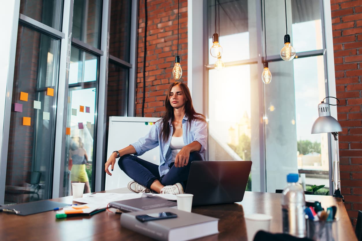 Woman in an office doing a yoga pose for physical and mental health for entrepreneurs